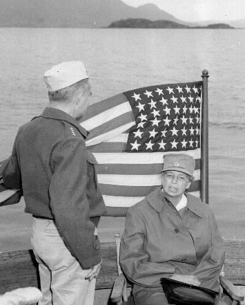 Eleanor Roosevelt in front of American flag on shipboard in Southwest Pacific in WWII